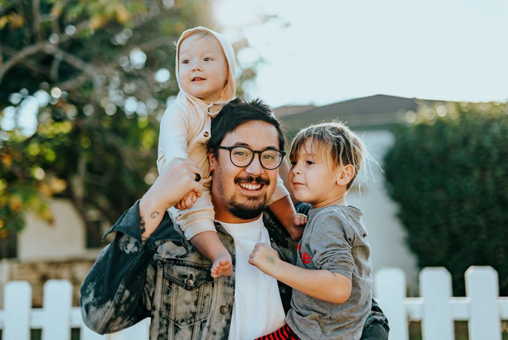 Glücklicher Familienvater mit seinen zwei Kindern auf dem Arm